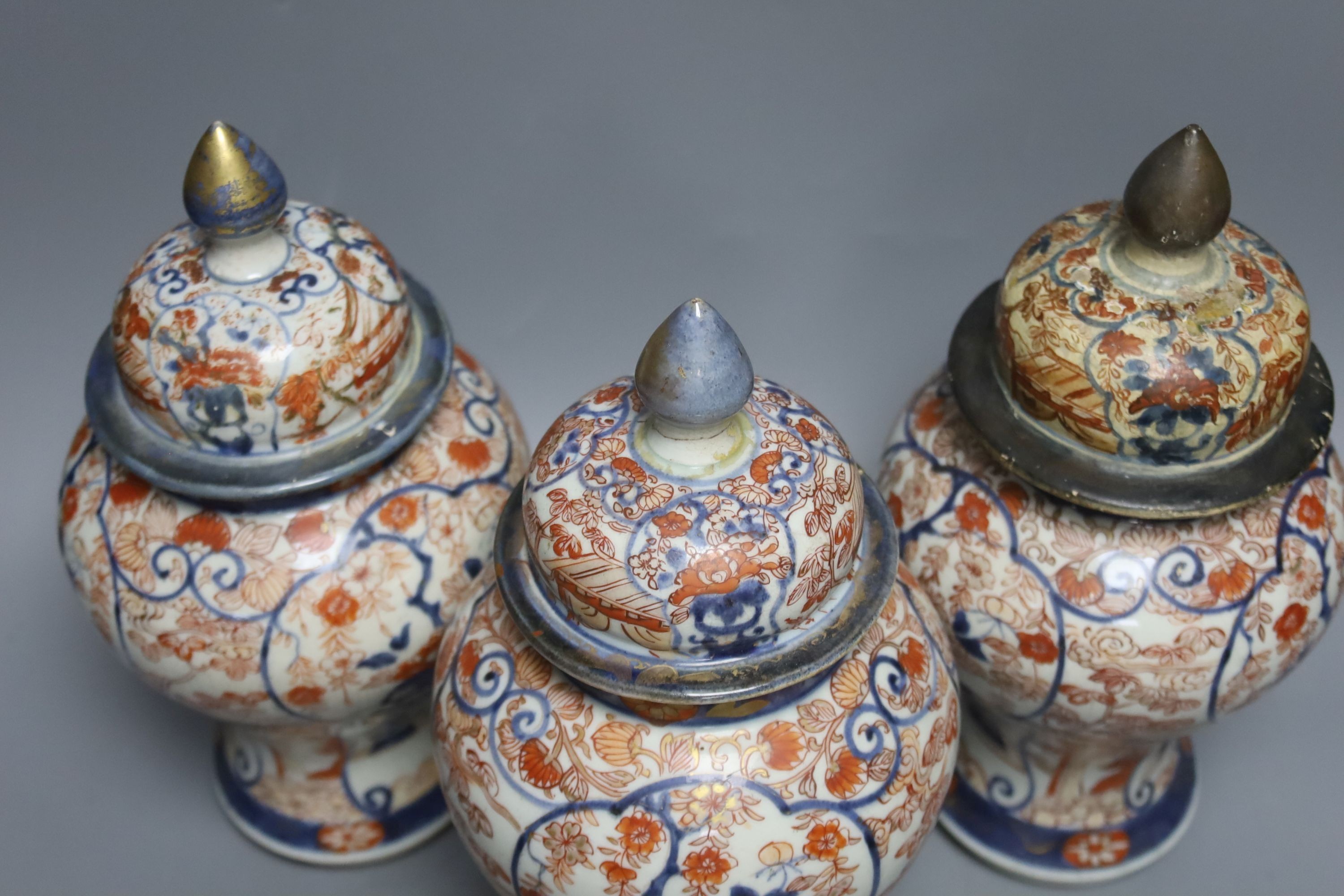 Three 18th century Japanese Arita baluster vases and covers decorated with flowers in urns (damage to covers) 29cm